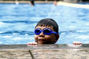 young boy with a pair of goggles in a swimming pool